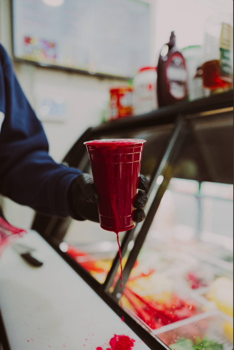 Fresh red juice being poured into a cup at the deli counter