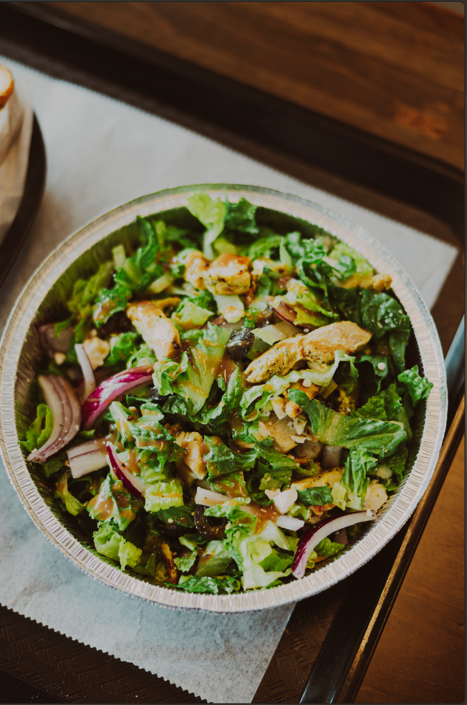 Chicken salad bowl with greens, olives, onions, and dressing