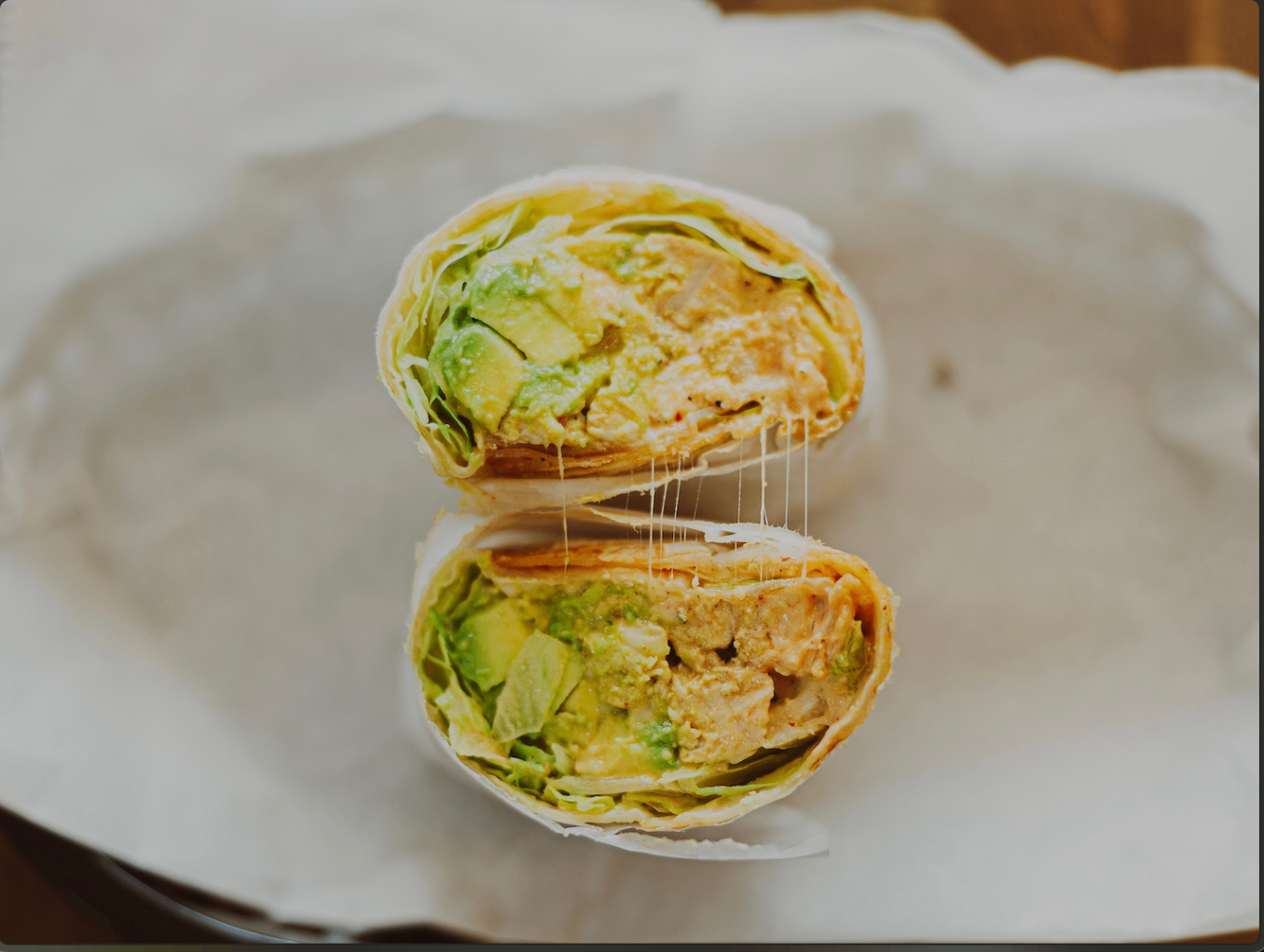 Grilled wrap cut in half with avocado and melted cheese
